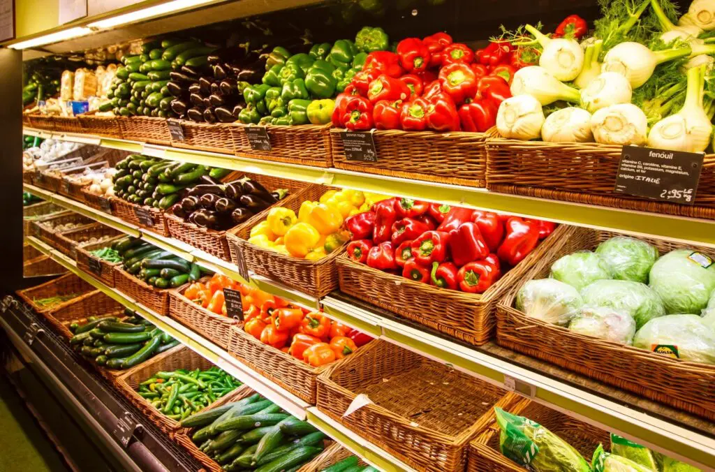 A display case filled with lots of different fruits and vegetables.