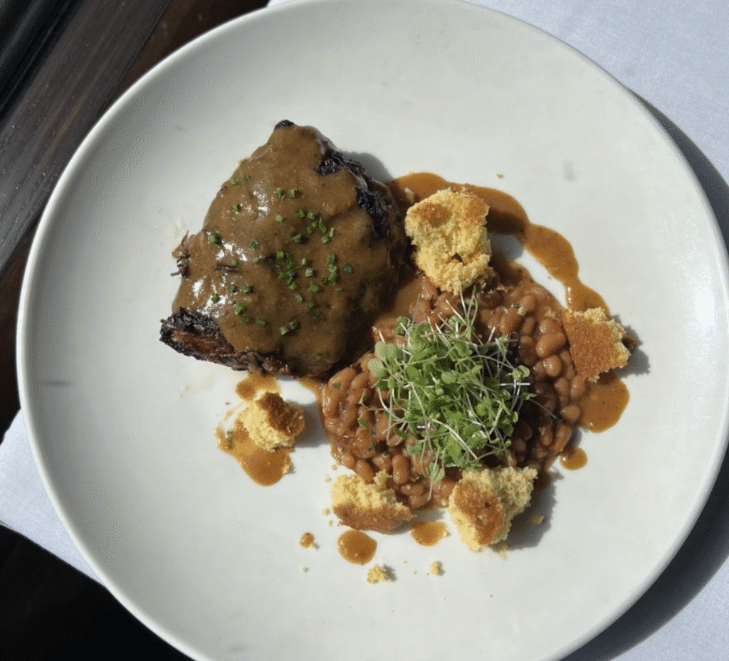 Steak with beans, cornbread, and garnish.