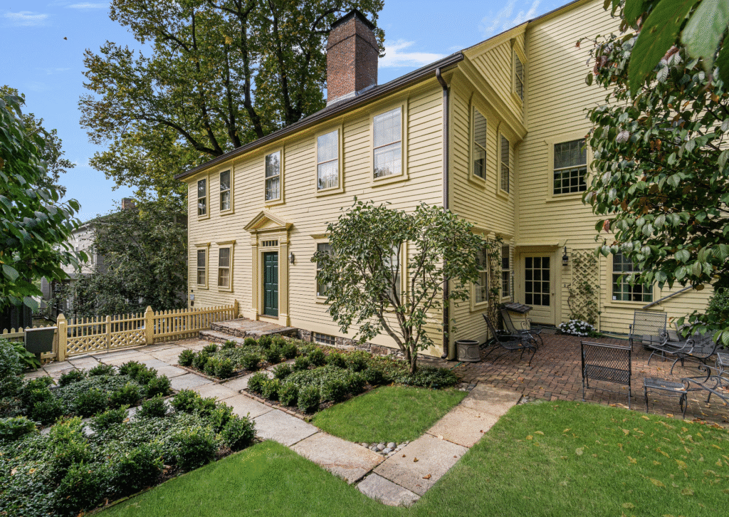 A large yellow house with a garden in the front yard.
