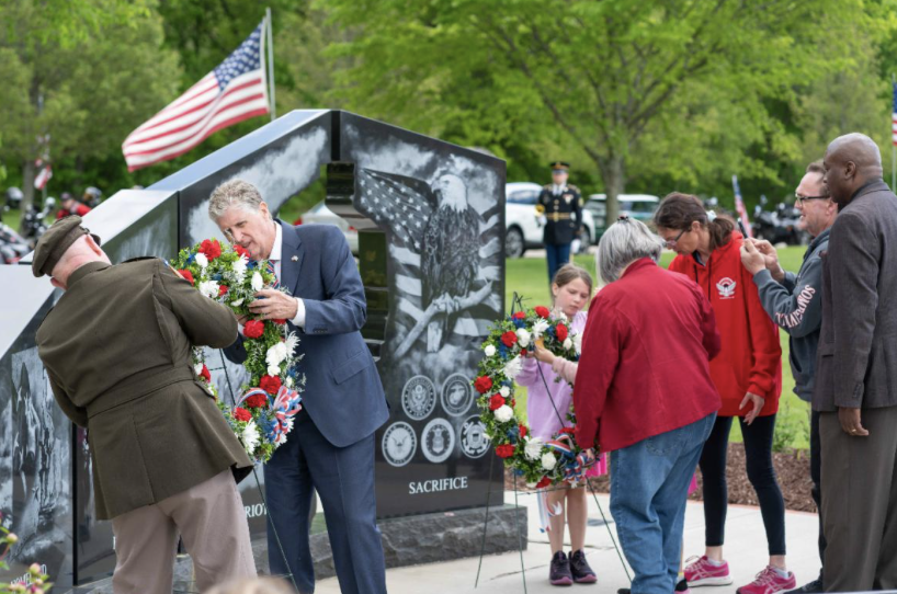A group of people standing around a memorial.