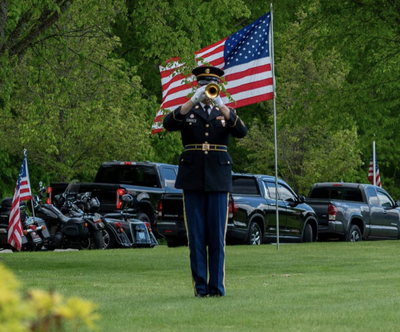 A man in uniform playing the trumpet with an american flag.