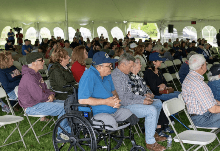 A group of people sitting in chairs under an awning.