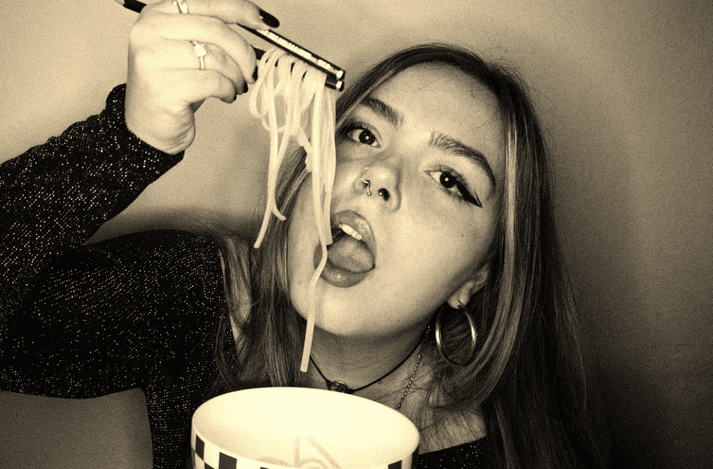 A woman eating noodles with chopsticks in her hand.