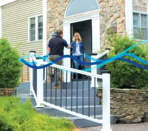 A man and woman standing on the steps of a house.