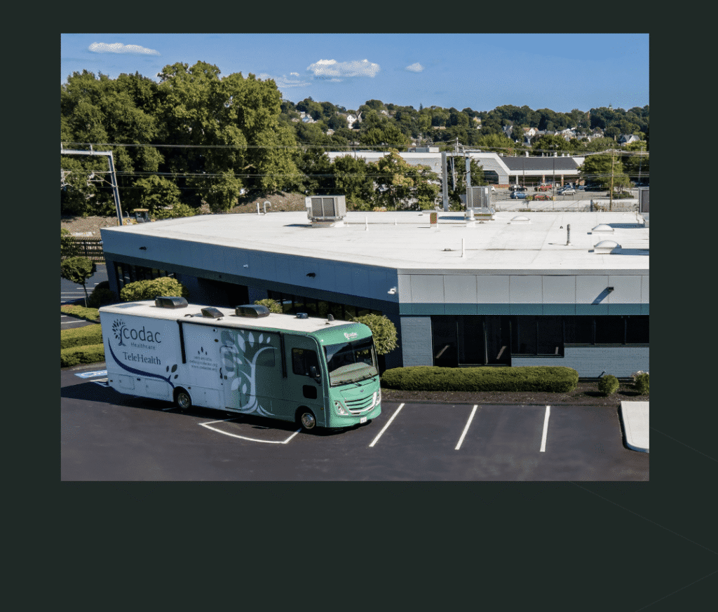 A green and white delivery truck parked outside a commercial building.
