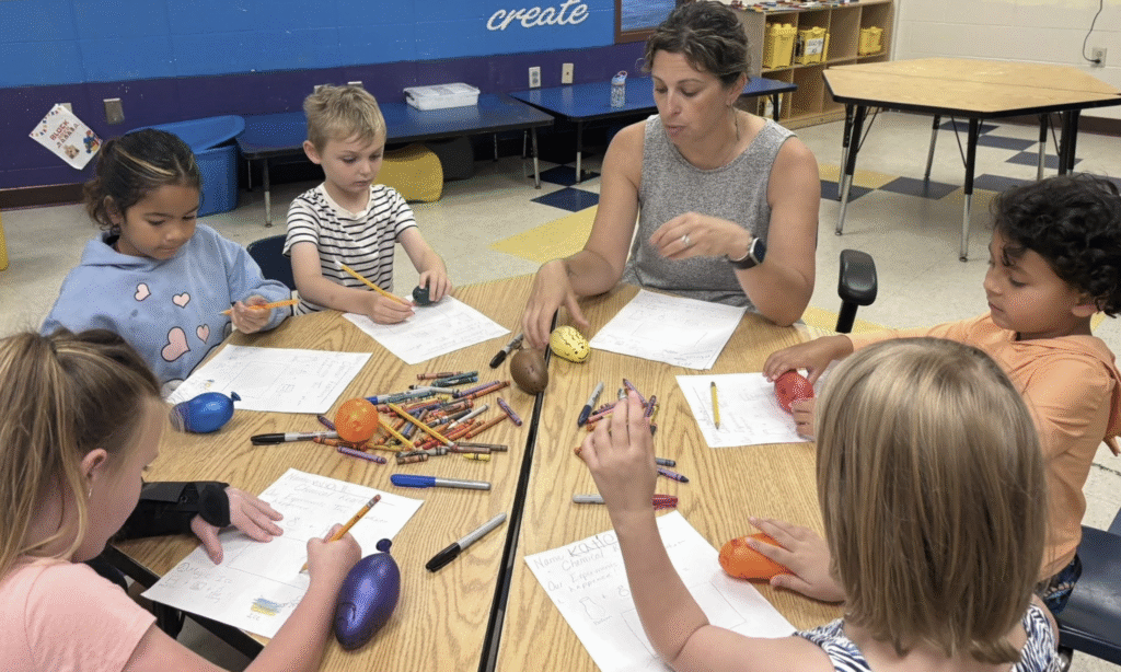 Children and a teacher engaged in a hands-on learning activity at a classroom table.