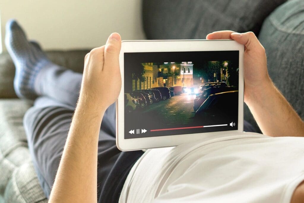 Person watching a cityscape video on a tablet while relaxing.