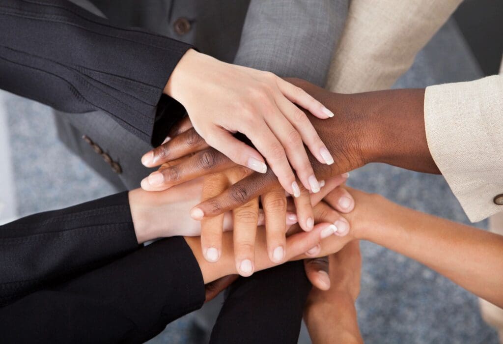 Hands of diverse people stacked together showing unity.