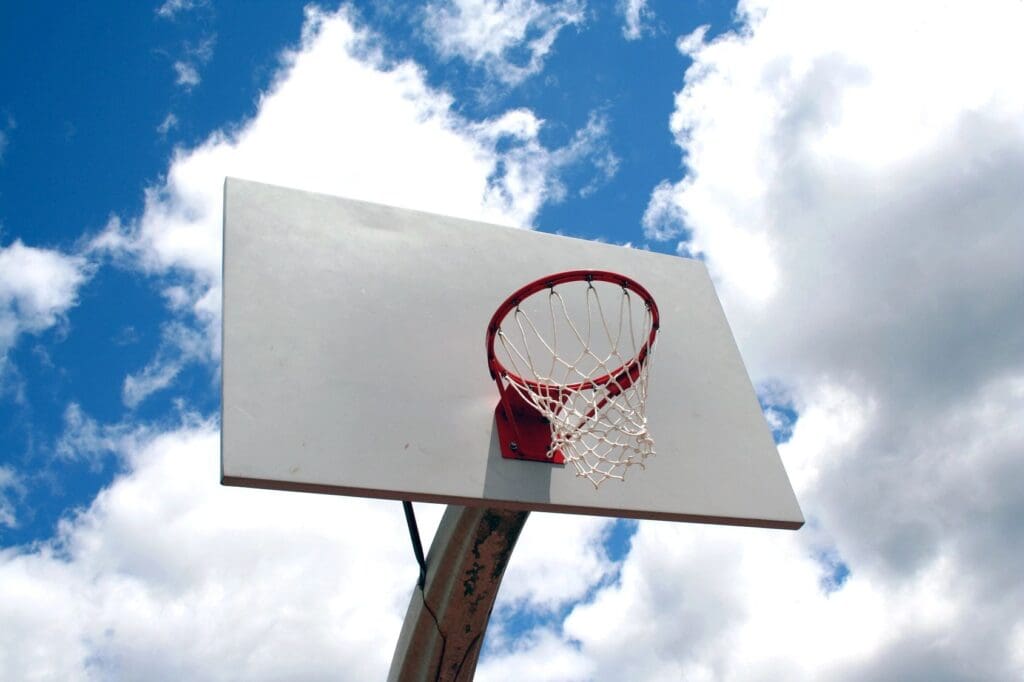 A basketball hoop and backboard under a partly cloudy sky.