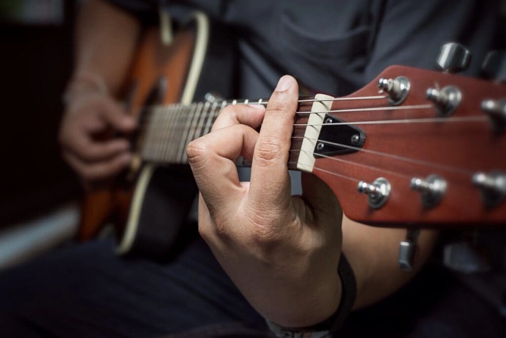 Close-up of hand playing chords on an acoustic guitar.