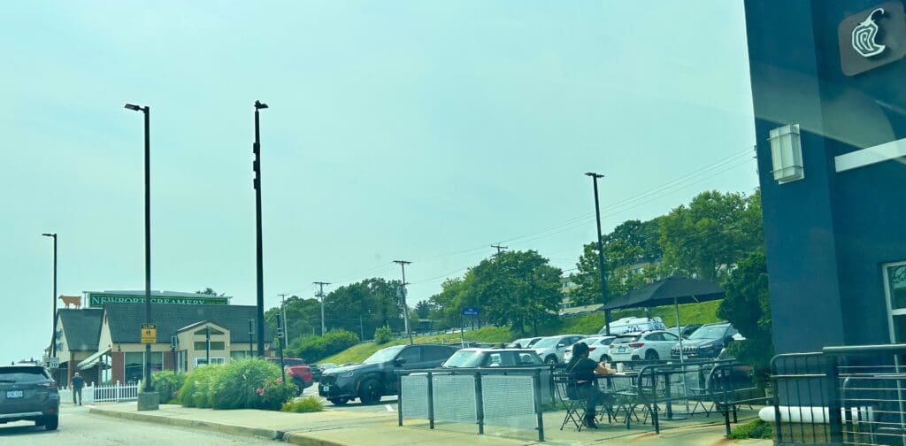 Cars parked near a fenced area with trees in the background.