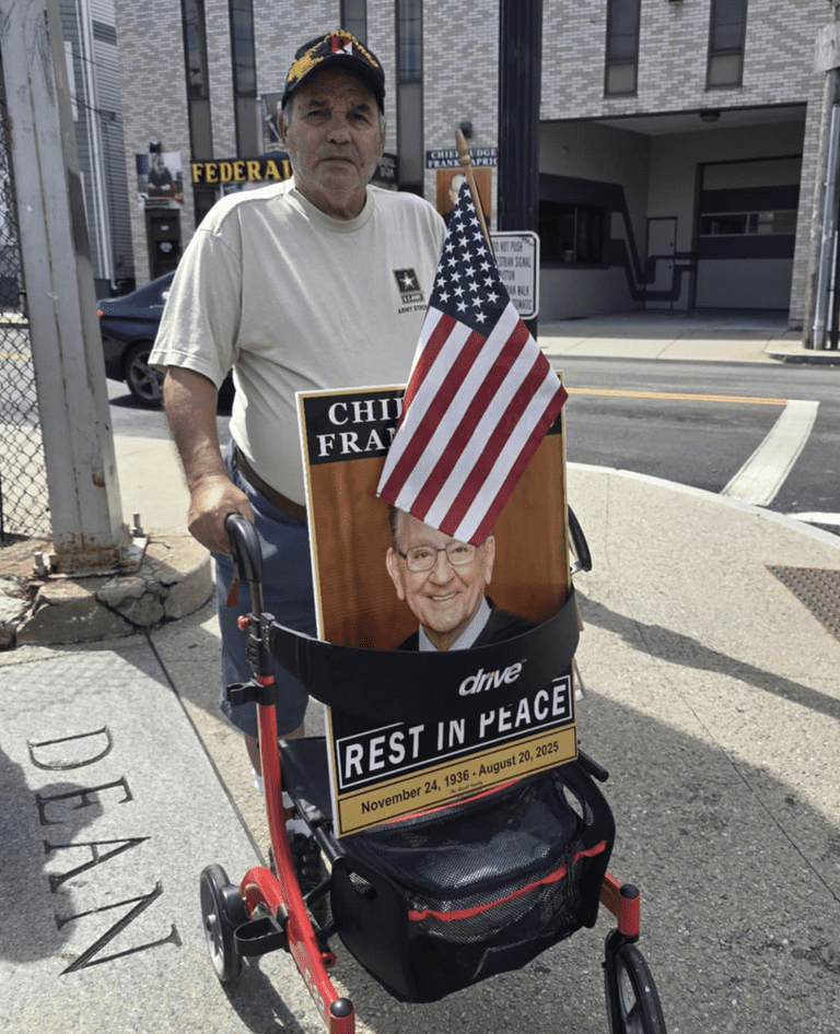Man holding an American flag and a sign honoring fallen firefighters.