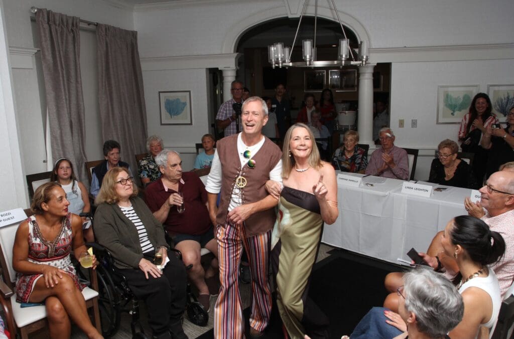 A man and woman dressed in vintage clothing smiling at a gathering.