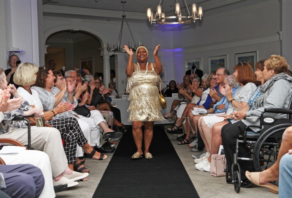 A joyful woman walks the runway in a playful dress at a lively fashion show.