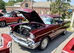 Classic maroon car with hood open at a car show.