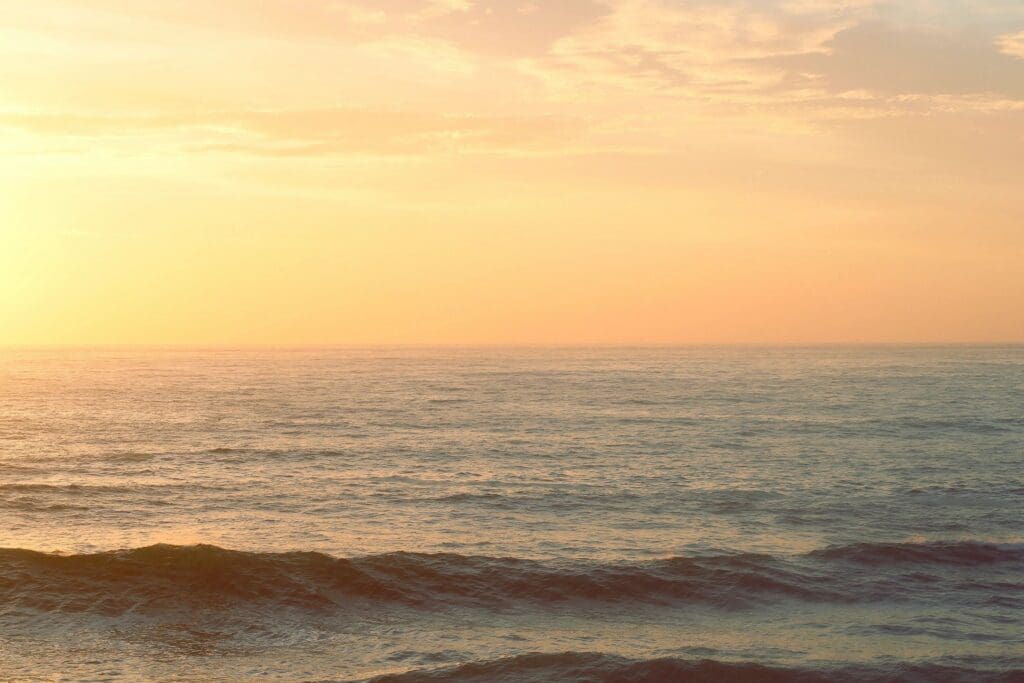 Serene ocean waves under a soft golden sunset sky.