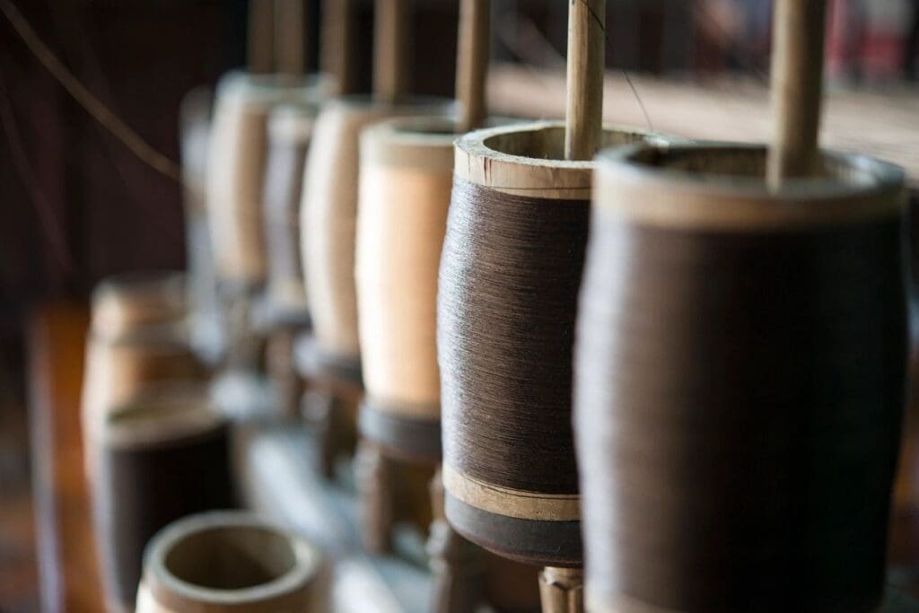 Close-up of yarn spools in various shades on a rack.