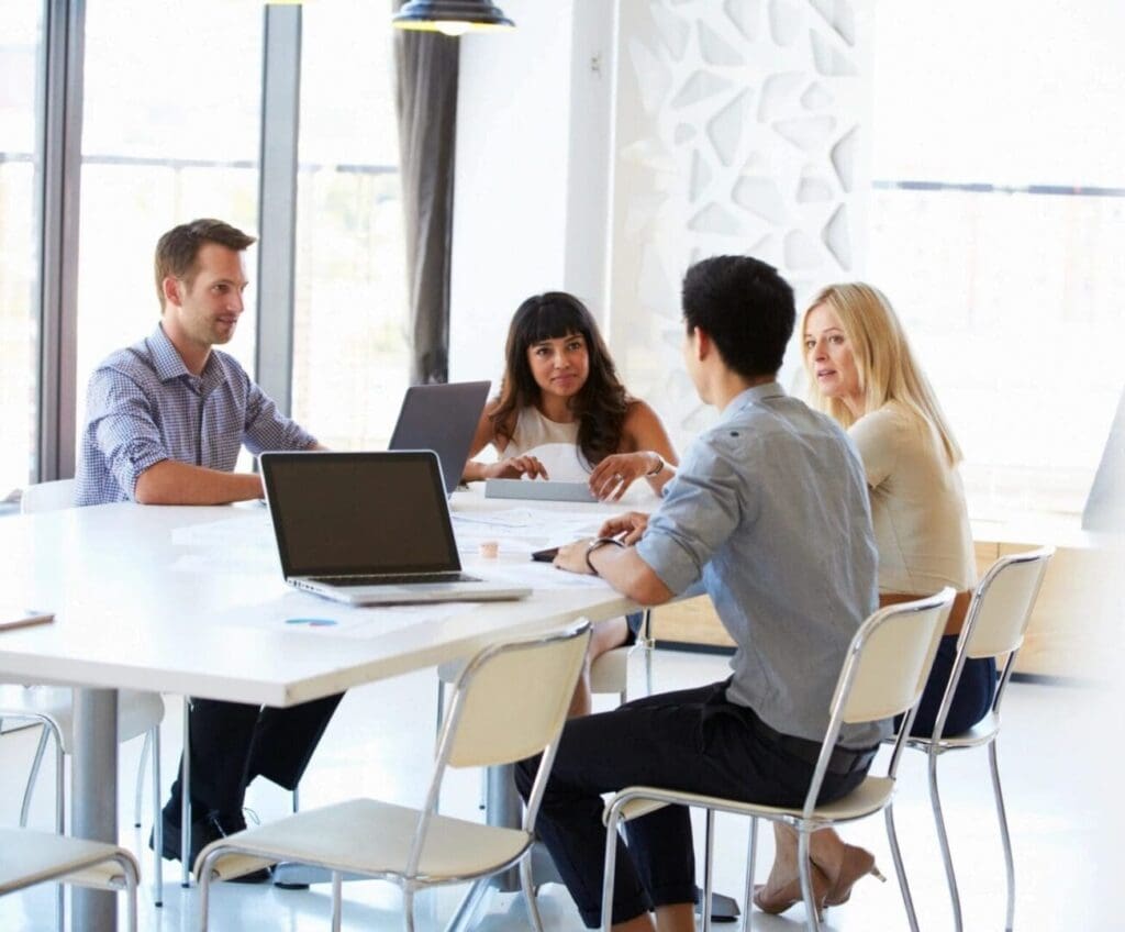 Four professionals having a meeting around a white table in a bright office.