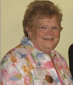 Smiling older woman wearing glasses and a floral blouse.