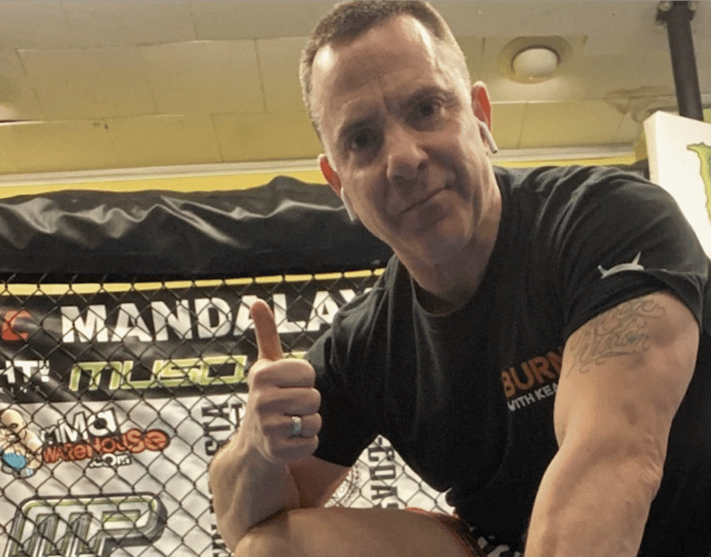 Man giving a thumbs-up in a gym setting.