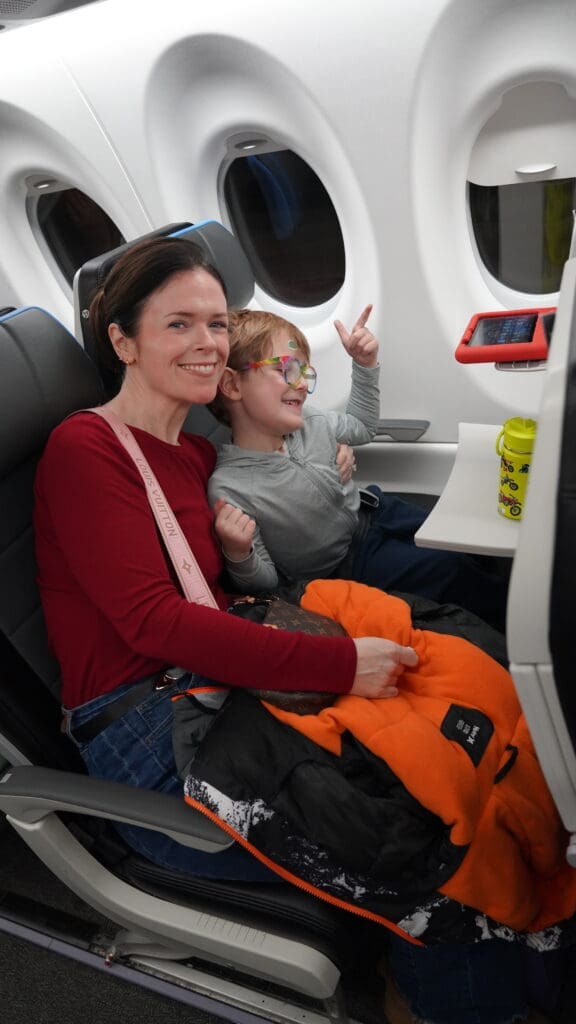 A smiling woman and child seated together on an airplane.