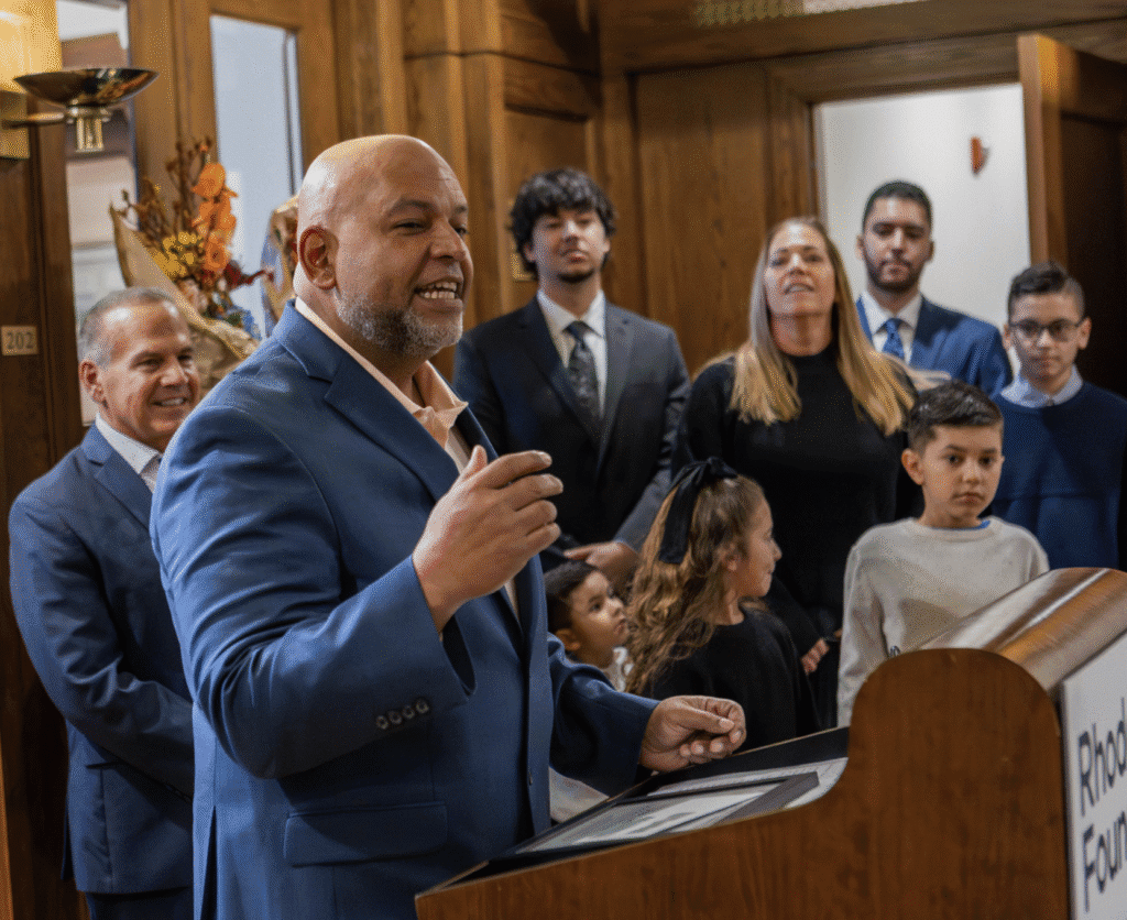 Man speaking at a podium during a formal event with attentive audience.