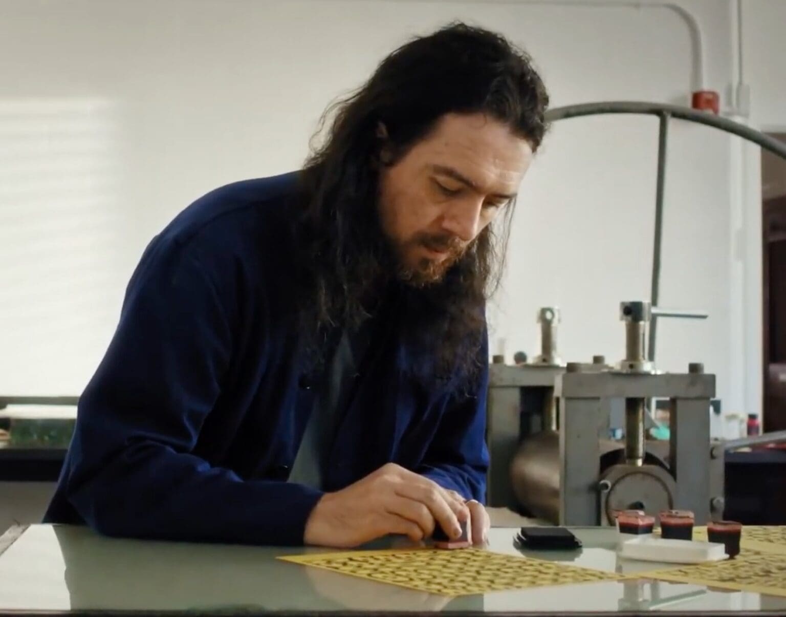 Man focused on crafting a small object at a workbench.