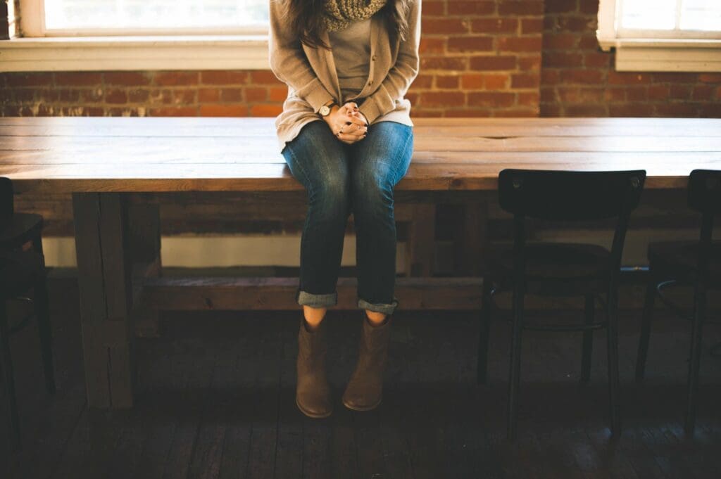 Person sitting on a bench tying shoelaces in a cozy indoor setting.