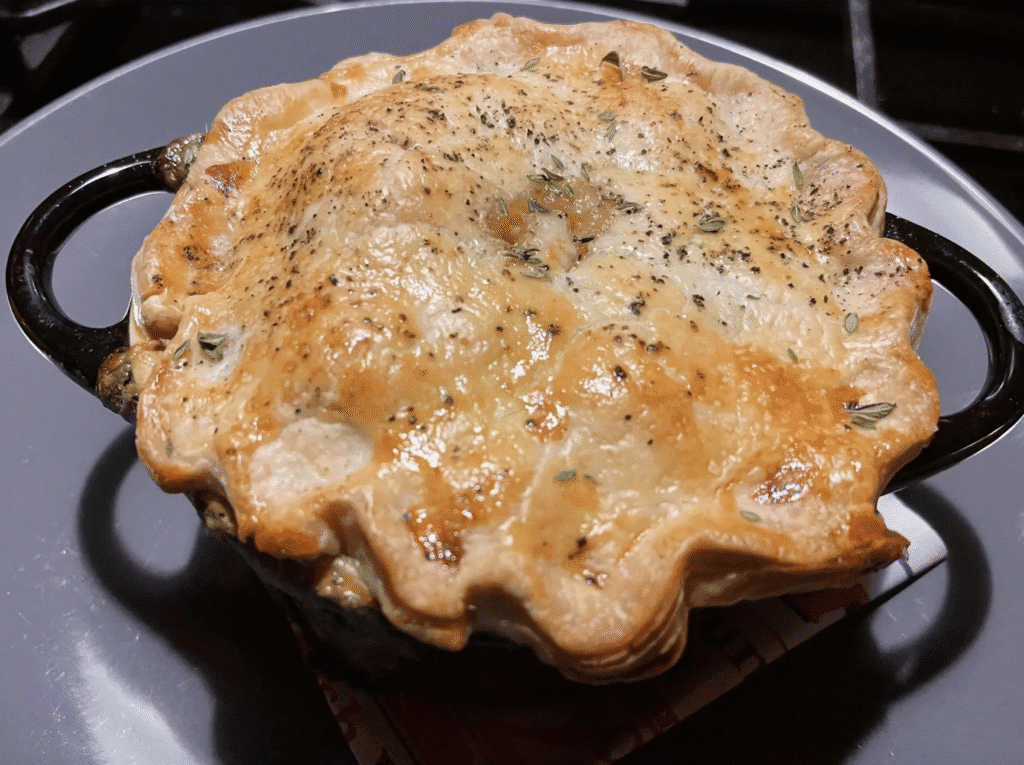 Golden-brown homemade pot pie with a flaky crust sprinkled with herbs.