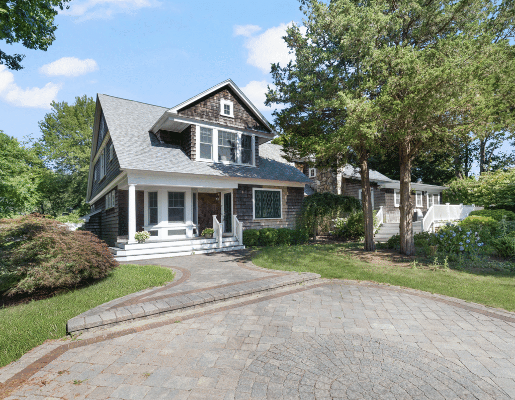 Charming two-story house with a spacious front porch and paved driveway.