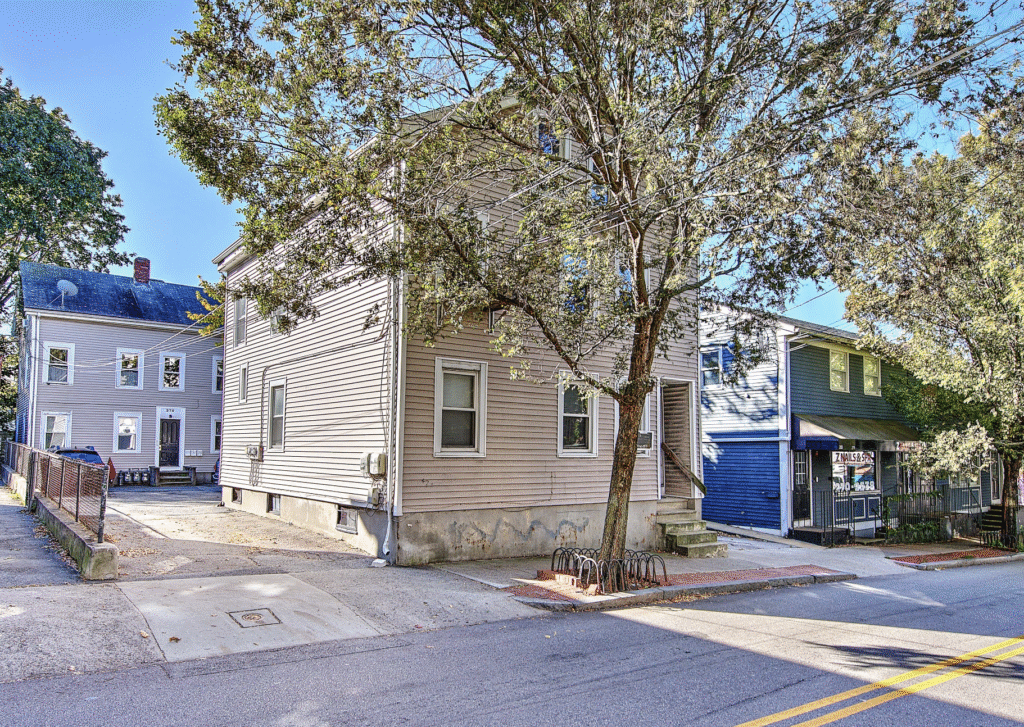 A beige brick building with a tree and a street intersection.