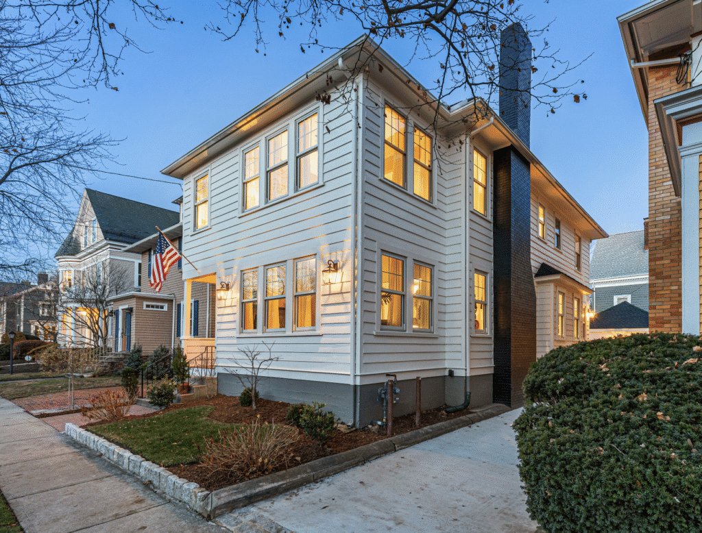Cozy two-story house with warm interior lights at dusk.