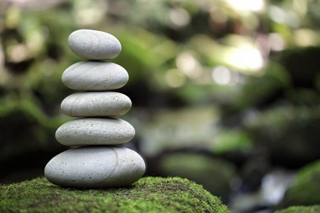 Stacked smooth stones balanced on mossy ground.