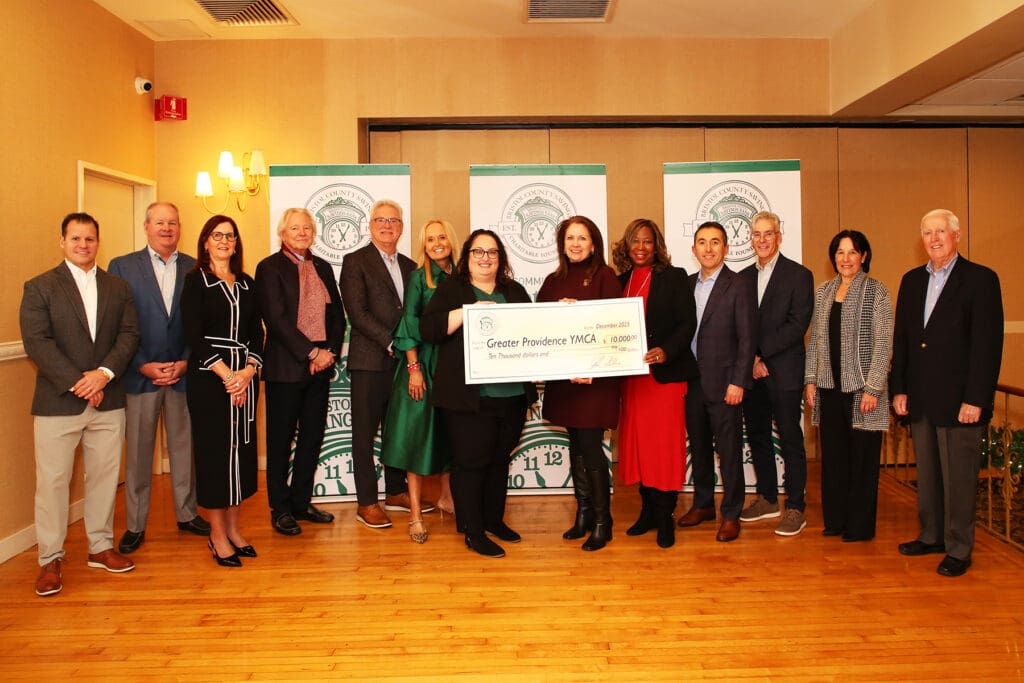 Group photo with a large check at an event in a warmly lit room.