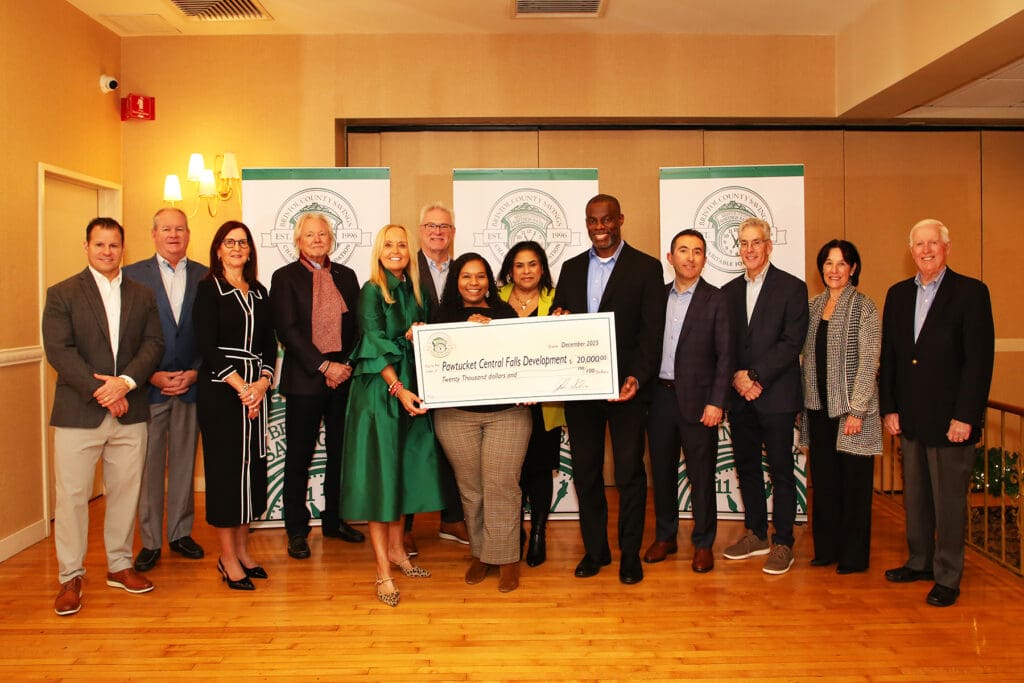 Group of people holding a large check at a formal event indoors.