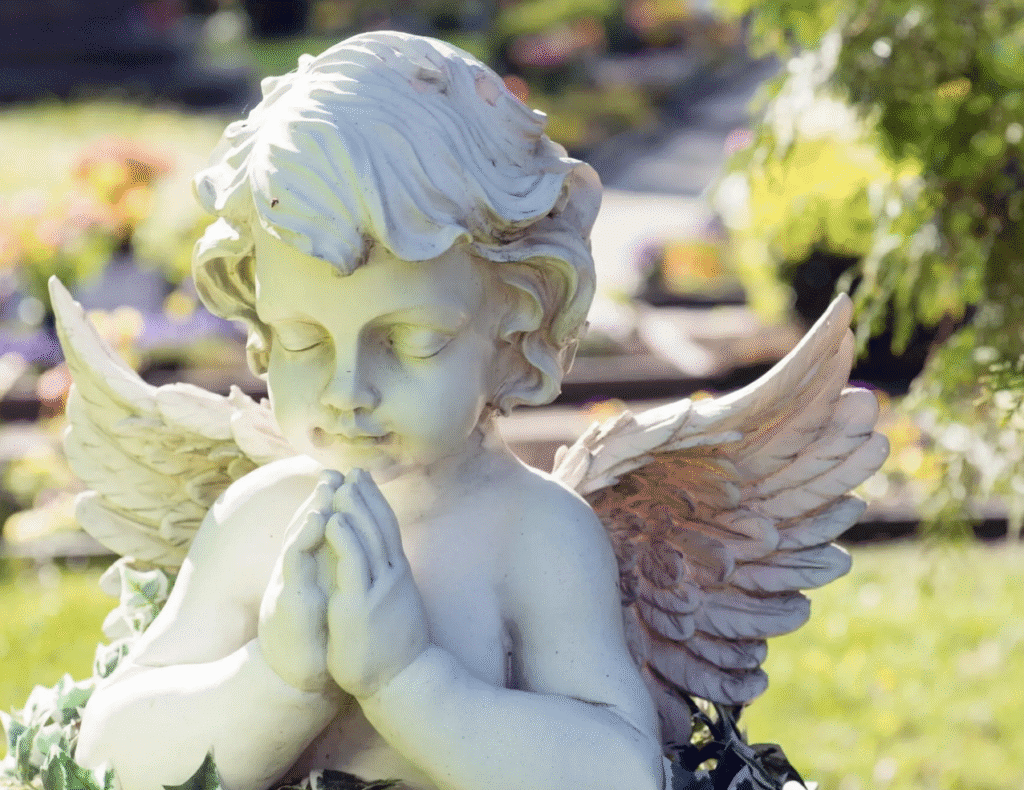 A cherubic angel statue with folded hands in prayer.