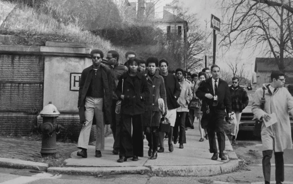 Black and white photo of protestors marching on a city street.