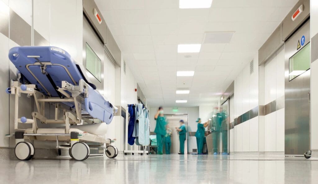 Medical staff in scrubs converse in a hospital corridor.