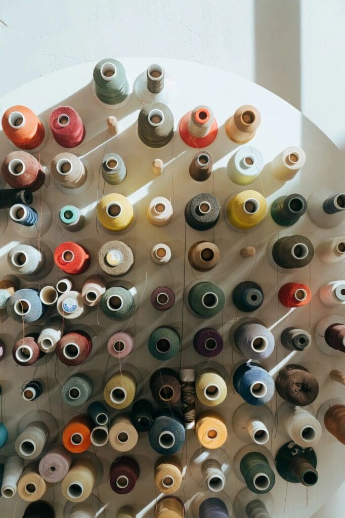 Top view of various colorful thread spools arranged closely together.