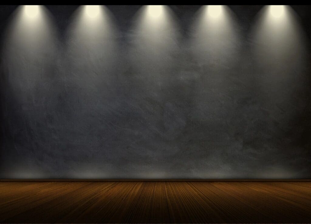 Empty stage with spotlight beams on a dark textured backdrop.