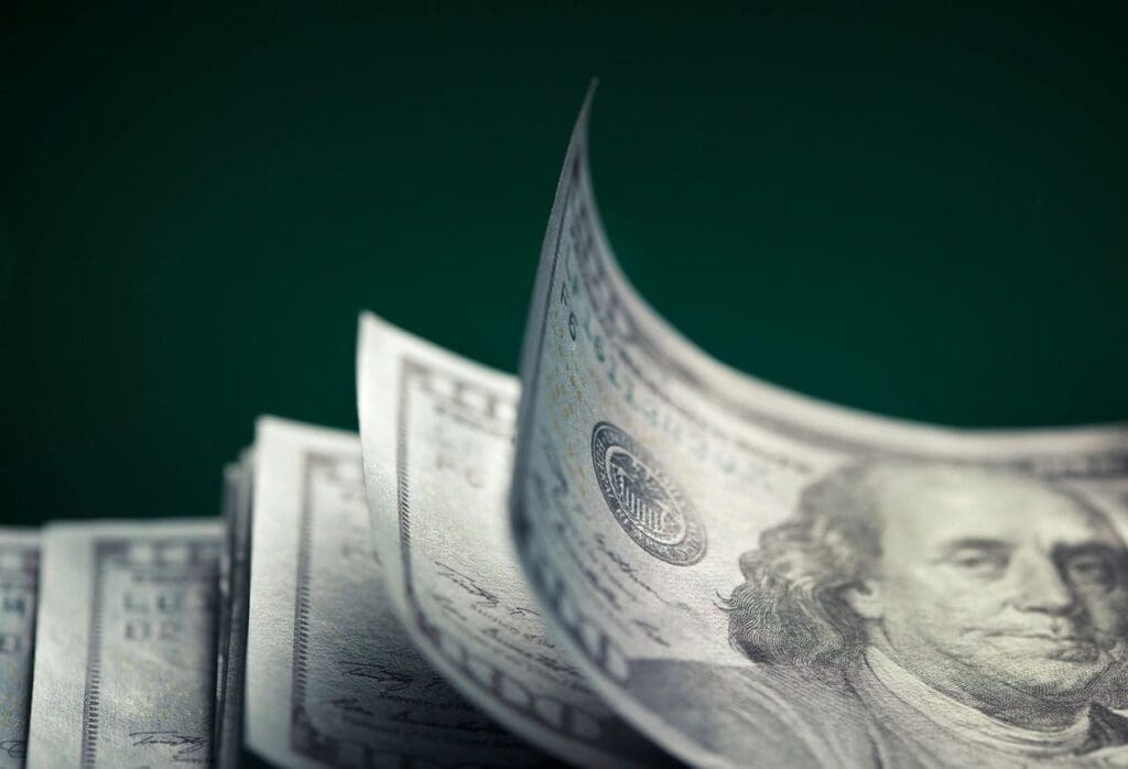 Close-up of US dollar bills with a dark green background.