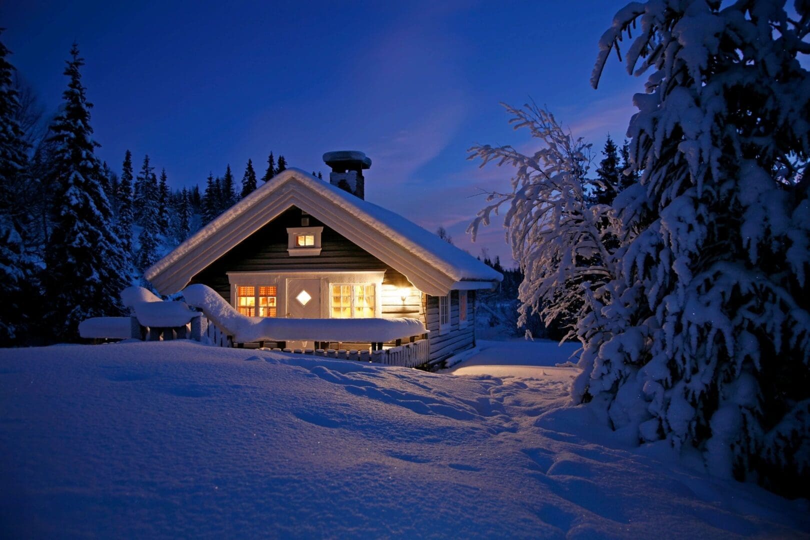 Cozy cabin warmly lit in snowy winter evening.