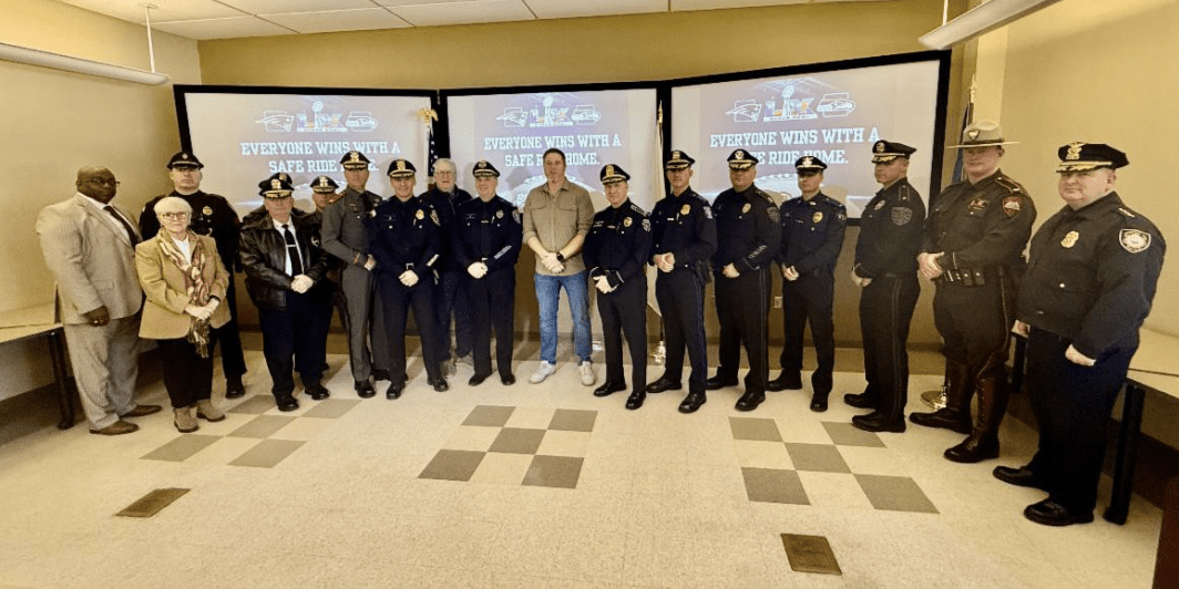 A group of uniformed officers standing with a man in casual attire indoors.