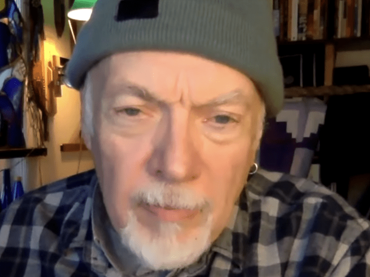 Elderly man wearing a green beanie and plaid shirt.