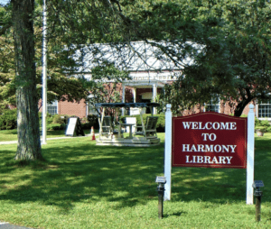Sign welcoming visitors to Harmony Library on a sunny day.