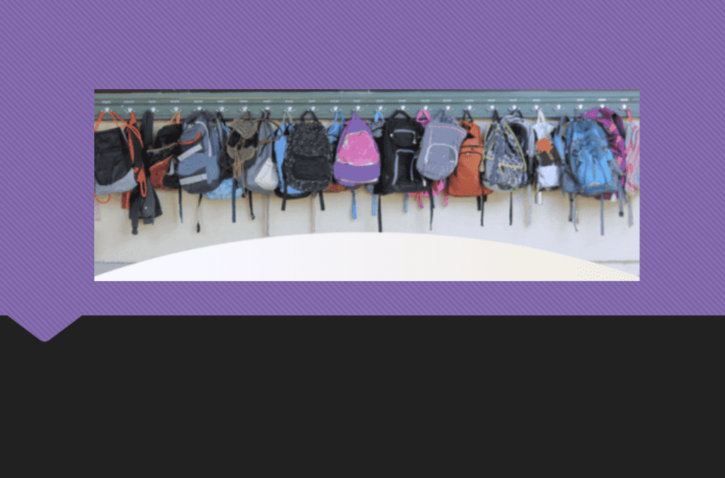 A row of various backpacks hanging on hooks against a purple wall.
