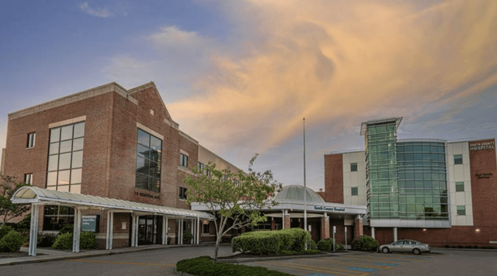 Modern brick and glass buildings under a cloudy sky at sunset.