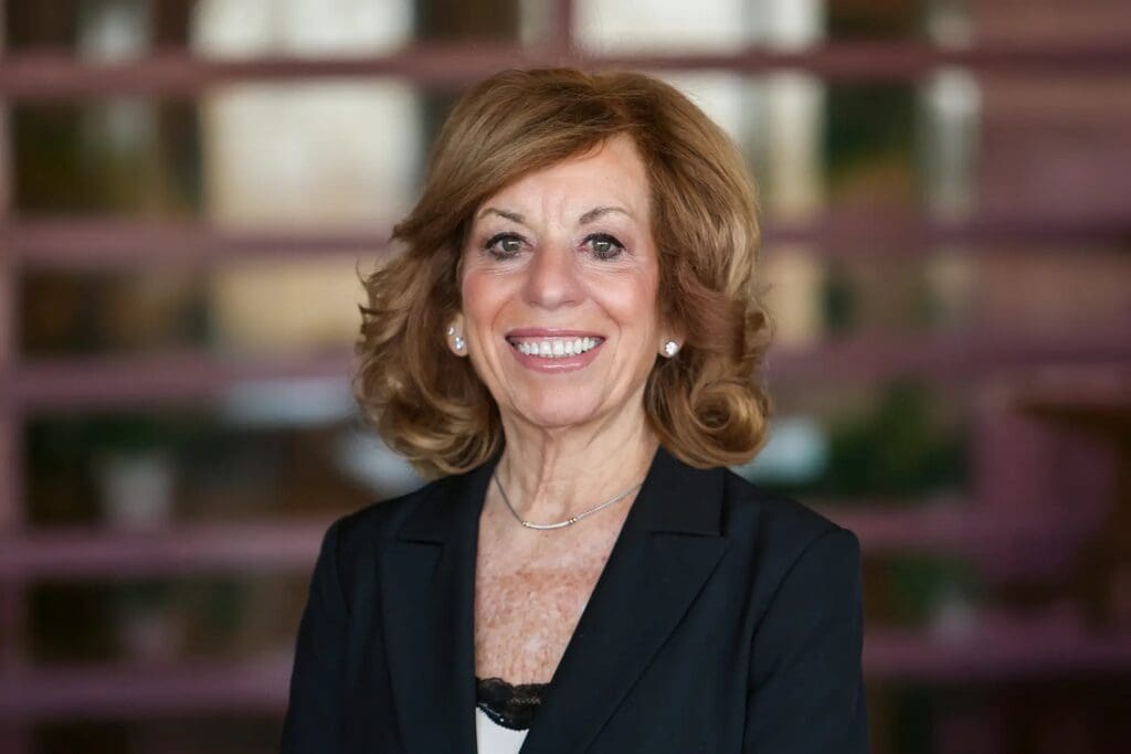Professional woman with curly hair smiling in an indoor setting.