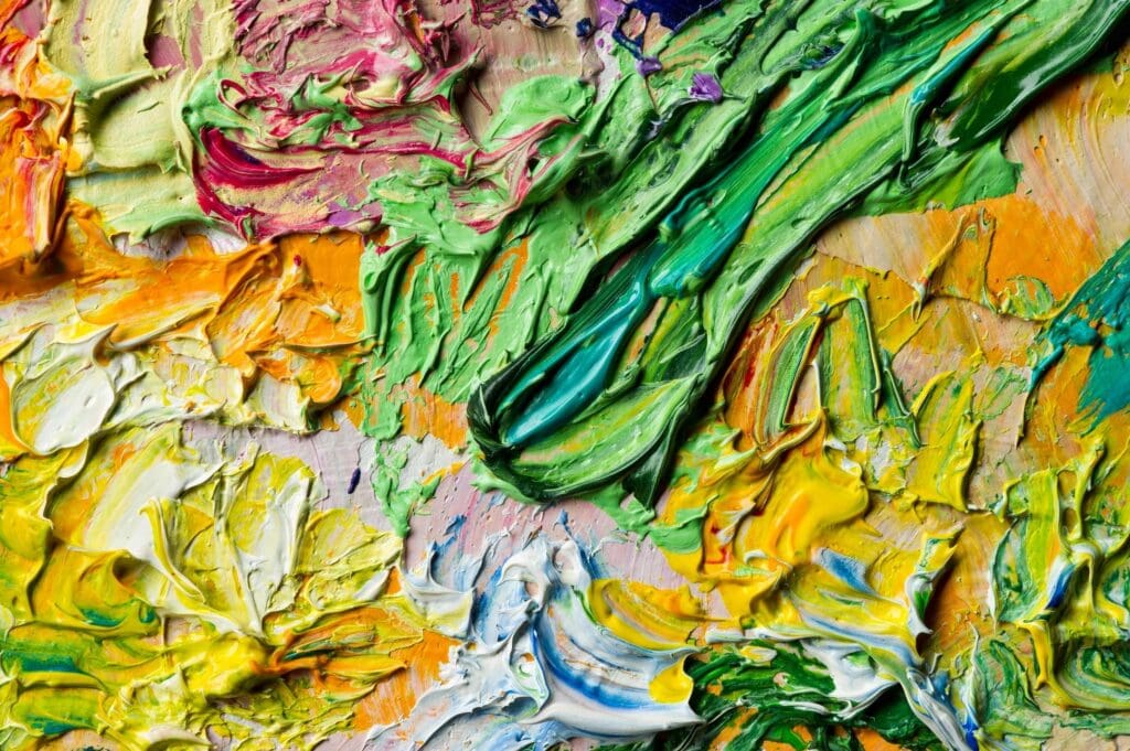 A close-up of thick, colorful paint strokes blending vibrant hues.