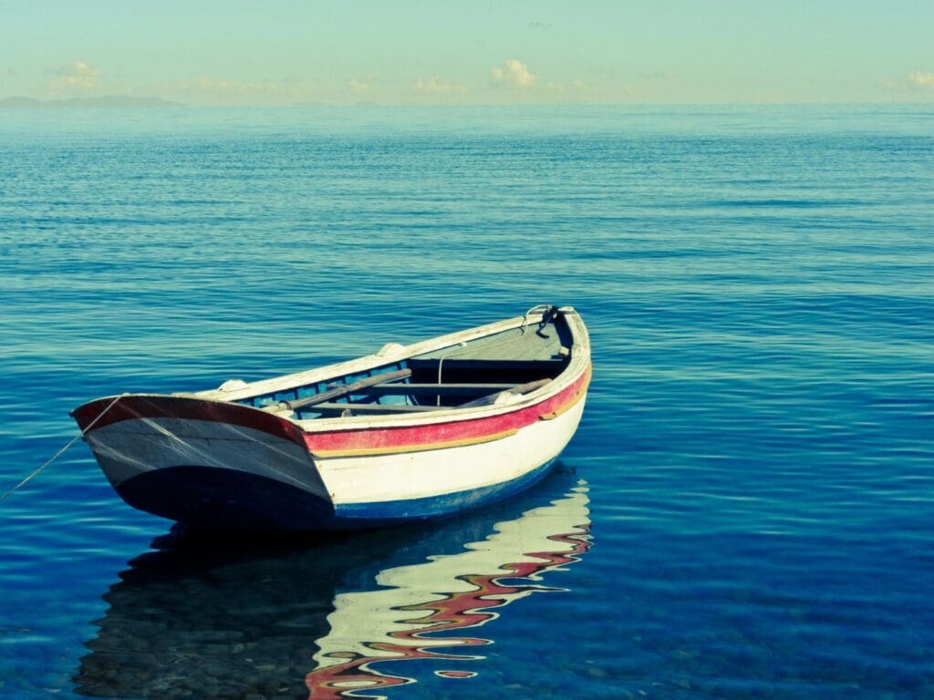 A small boat floating calmly on serene blue waters under a clear sky.